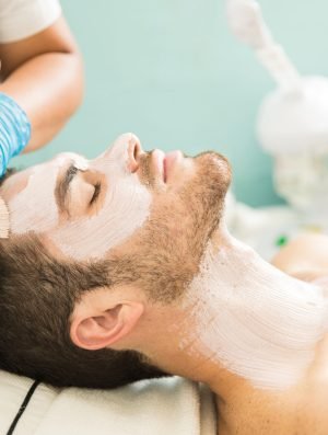 Profile view of a young man getting a moisturizing facial treatment in a health spa