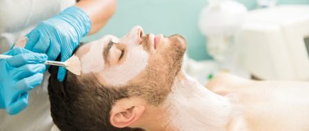 Profile view of a young man getting a moisturizing facial treatment in a health spa